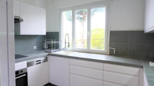 une cuisine blanche avec un évier et une fenêtre dans l'établissement Proche Croisette, Appartement 2 Chambres by Palmazur Vacances, à Cannes