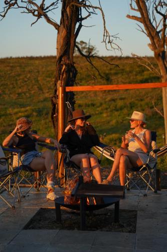 a group of people sitting around a fire at Sunvale Stunning Luxury Lodge with Woodfire Heated Spa and Large Deck in Capertee