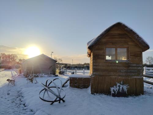 une cabane en rondins dans la neige avec le soleil en arrière-plan dans l'établissement Chalet David Hockney, à Saint-Germain-dʼAunay