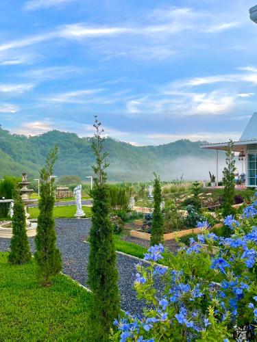 a garden with blue flowers in the foreground at Tiny Escape Charlotte in Pak Chong