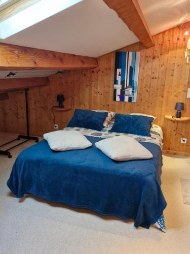 - une chambre avec un lit bleu et des oreillers blancs dans l'établissement Le refuge, à Bédarrides