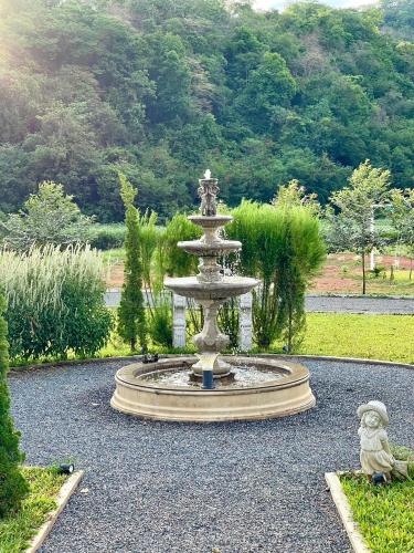a fountain in a garden with a dog sitting next to it at Tiny Escape Charlotte in Pak Chong