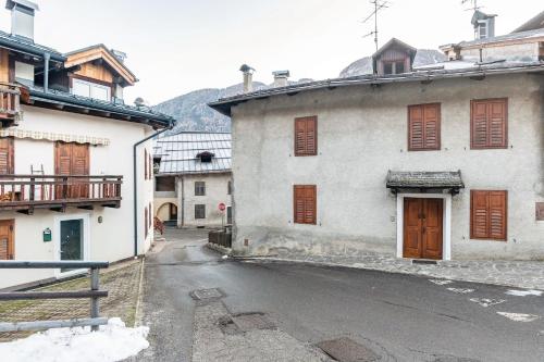 an old white building with brown shutters on a street at Appartamento Condominio Genziana in Monclassico