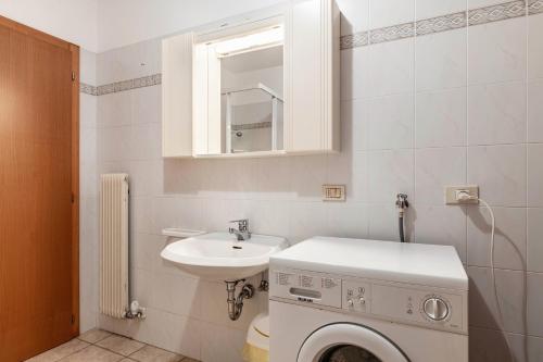 a bathroom with a washing machine and a sink at Appartamento Condominio Genziana in Monclassico