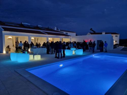 a group of people standing around a pool at night at Monte de São Francisco Country House in Vale de Maceira