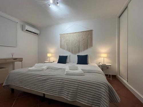 a white bedroom with a large bed with blue pillows at Monte de São Francisco Country House in Vale de Maceira