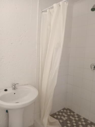 a bathroom with a sink and a white shower curtain at Baksman's Retreat in Soweto