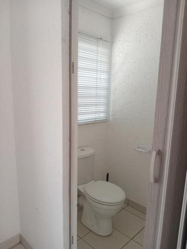a white bathroom with a toilet and a window at Baksman's Retreat in Soweto
