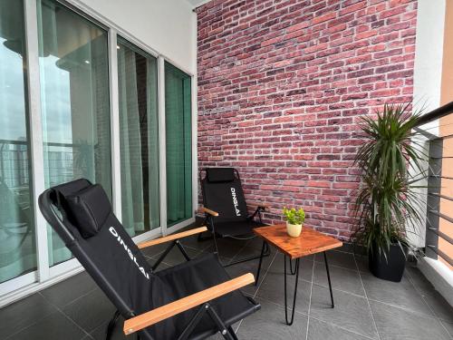 two chairs and a table on a balcony with a brick wall at Industrial Luxe Concrete Bliss, near Sunway Pyramid,Subang Jaya in Subang Jaya