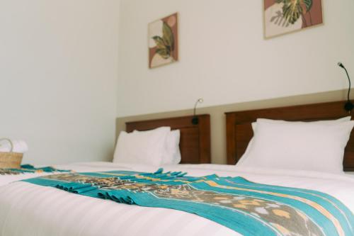 a white bed with a colorful blanket on it at Escape Bajo in Labuan Bajo