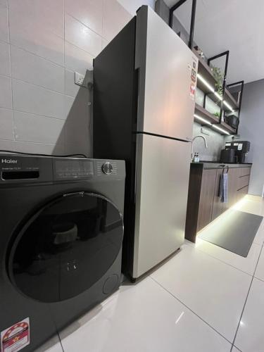a kitchen with a refrigerator and a washing machine at Industrial Luxe Concrete Bliss, near Sunway Pyramid,Subang Jaya in Subang Jaya