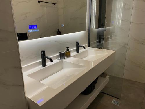 ein Badezimmer mit einem weißen Waschbecken und einem Spiegel in der Unterkunft Angel's Apartment Volos in Volos