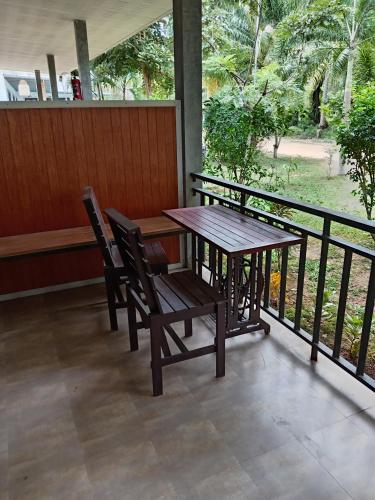 a wooden table and chairs on a porch with a view at Lantacocogarden in Ko Lanta Yai