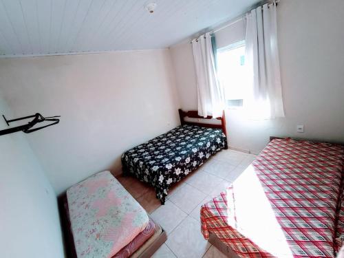 um pequeno quarto com uma cama e uma janela em Nosso Sonho em Rio das Ostras