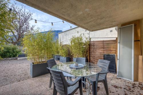 un patio extérieur avec une table et des chaises en verre dans l'établissement Évasion Thailandaise - Feng Shui - Parking, à Saint-Égrève