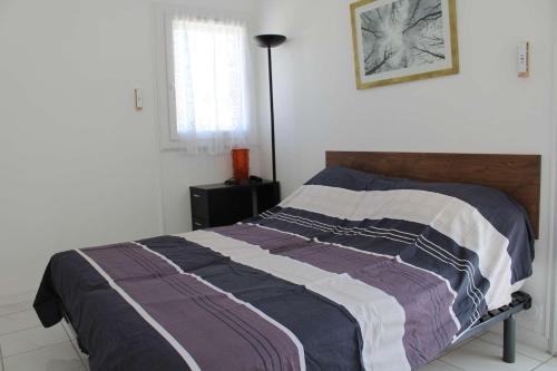 une chambre avec un lit avec une couverture dessus dans l'établissement PN000-053 Maison 6 couchages - PORT LA NOUVELLE, à Port-la-Nouvelle