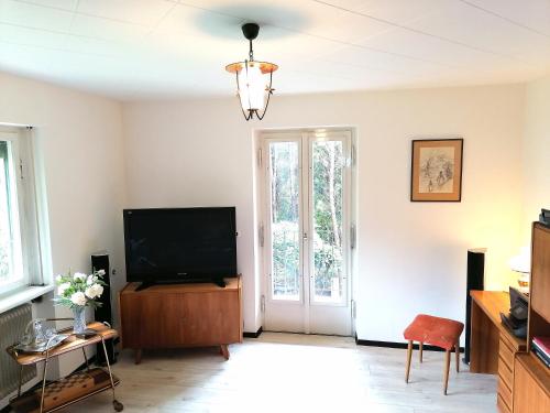 a living room with a flat screen tv on a wooden cabinet at Dimai House 1970s in Hohenems