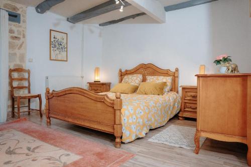 a bedroom with a wooden bed and a chair at Dordogne - Belle maison pour 8 avec piscine in Saint-Rabier