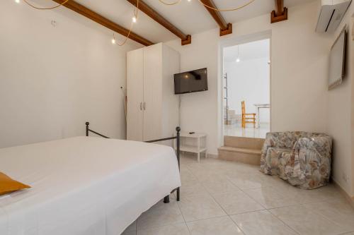 a bedroom with a white bed and a chair at Antiche Mura Apartments"Cielo di Puglia" -2 matrimoniali, cucina e terrazzo in Turi