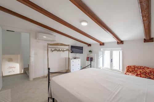a bedroom with a white bed and a tv at Antiche Mura Apartments"Cielo di Puglia" -2 matrimoniali, cucina e terrazzo in Turi