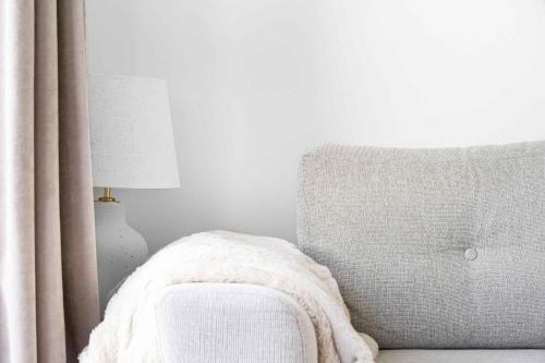 a bedroom with a couch and a lamp and a chair at Newly Renovated Holiday Apartment On Bornholm in Neksø