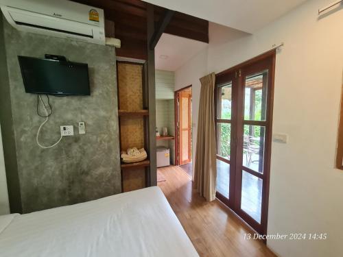 a bedroom with a bed and a tv on the wall at Koh Mak Living in Ko Mak