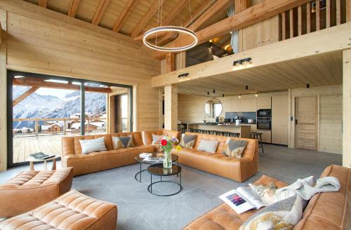 Il comprend un grand salon avec des canapés et une cuisine. dans l'établissement Odalys Chalet L'Ours Polaire, à Les Deux Alpes