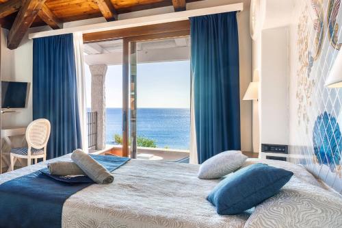 a bedroom with a bed with a view of the ocean at Hotel La Bitta - Bovis Hotels in Àrbatax