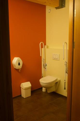 a bathroom with a toilet and orange walls at Laugarfell Accommodation & Hot Springs in Laugarfell