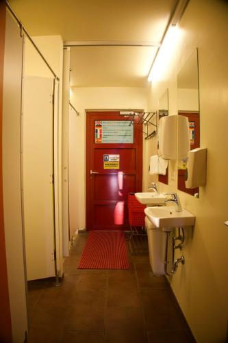 a bathroom with two sinks and a red door at Laugarfell Accommodation & Hot Springs in Laugarfell