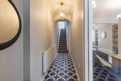 a hallway with a staircase with blue and white tiles at Eller Cottage in Windermere