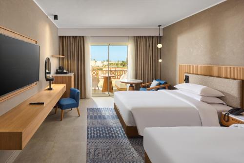 a hotel room with two beds and a flat screen tv at Sheraton Soma Bay Resort in Hurghada