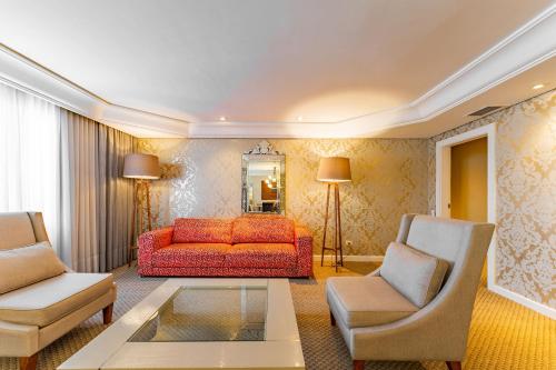 a living room with a red couch and two chairs at Grand Mercure Curitiba Rayon in Curitiba
