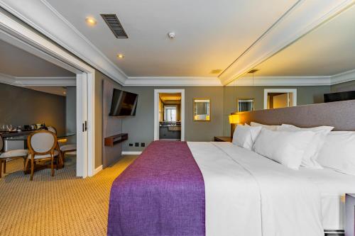 a bedroom with a large bed and a table at Grand Mercure Curitiba Rayon in Curitiba