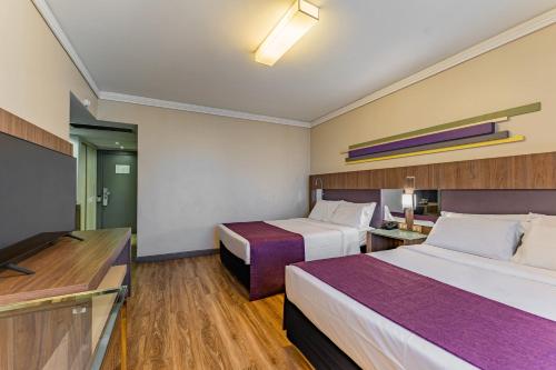 a hotel room with two beds and a flat screen tv at Grand Mercure Curitiba Rayon in Curitiba