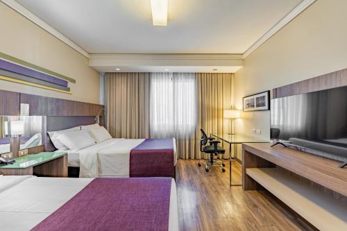 a hotel room with a bed and a desk at Grand Mercure Curitiba Rayon in Curitiba