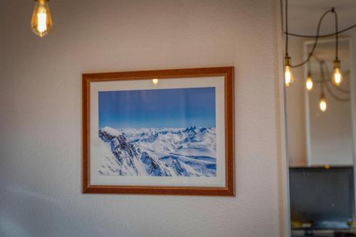 a picture of a snow covered mountain on a wall at L'AlpinEscapade - Parking - Ski in Chamrousse