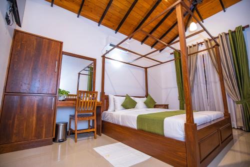 a bedroom with a canopy bed and a chair at Villa Freedom in Hikkaduwa