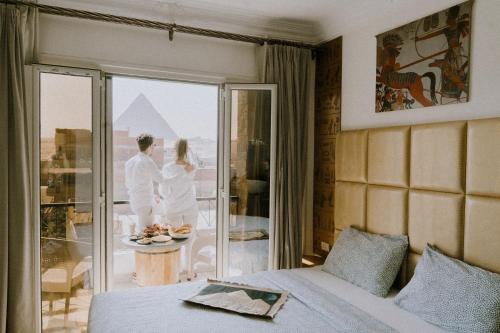 ein Paar steht auf einem Balkon in einem Hotelzimmer in der Unterkunft BrassJimmy pyramids view in Kairo