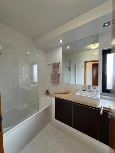 a bathroom with a sink and a tub and a mirror at Praia da Luz - Resort in Luz