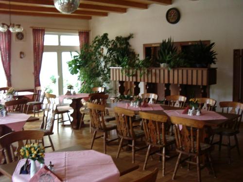 a dining room with tables and chairs and plants at Pension Am Rheinsberger Schloßpark in Rheinsberg