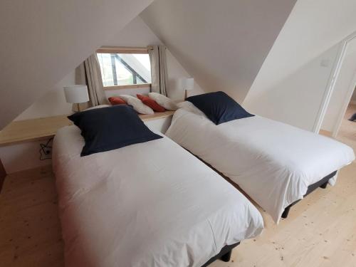 two beds in a attic room with a window at La grange de Rose et François in Le Conquet
