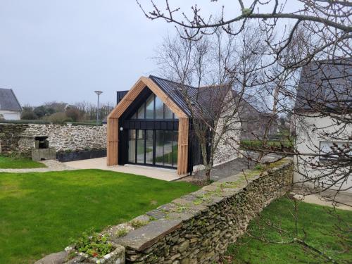 a house with a wooden roof and a stone wall at La grange de Rose et François in Le Conquet