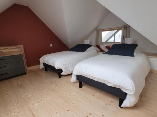 a attic bedroom with two beds and a window at La grange de Rose et François in Le Conquet