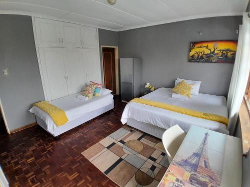a bedroom with two beds and a table in it at 54 Malcolm Hidden Gem near Musgrave in Durban