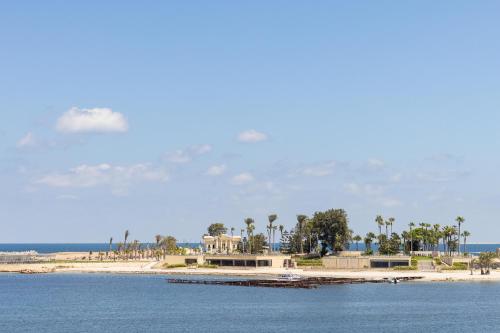 a beach with a house and palm trees and the water at Rixos Montaza Alexandria in Alexandria