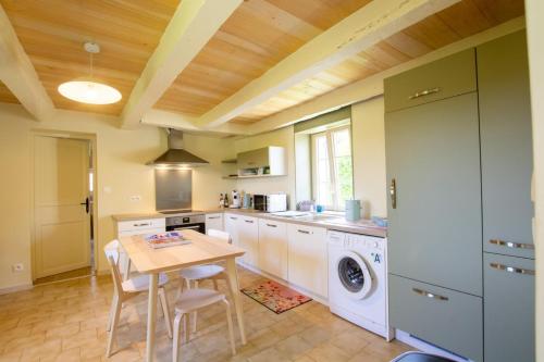 - une cuisine avec une table et un lave-linge/sèche-linge dans l'établissement La maison de mamie, à Allemans