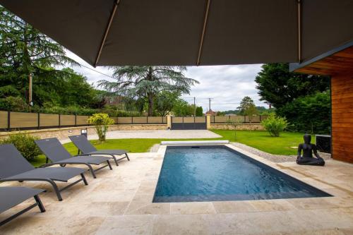 a swimming pool in a yard with chairs and an umbrella at Gite de la fontanelle in Anlhiac