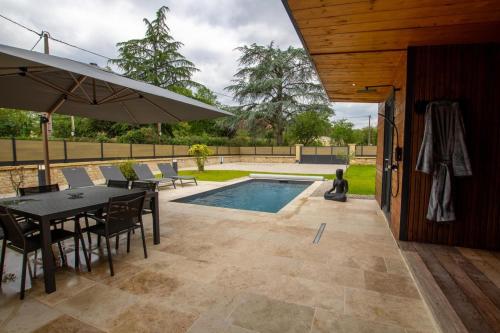 a patio with a table and chairs and a pool at Gite de la fontanelle in Anlhiac
