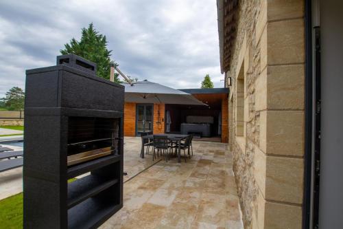an outdoor kitchen with a black oven next to a building at Gite de la fontanelle in Anlhiac